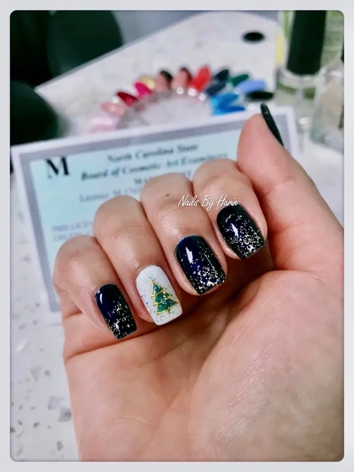 Deep blue holiday gel manicure with gold sparkle and a hand-painted tree, by Harin