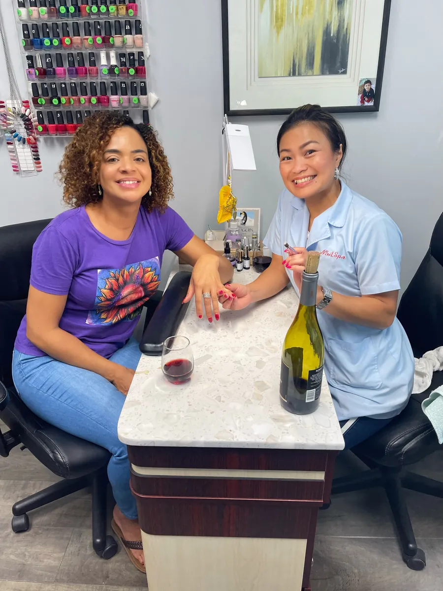 Harin giving a client a relaxed manicure over a glass of wine at Ultimate Beauty Salon