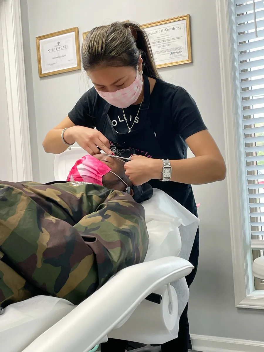 Harin shaping a client's eyebrows — brow waxing is offered alongside nail care